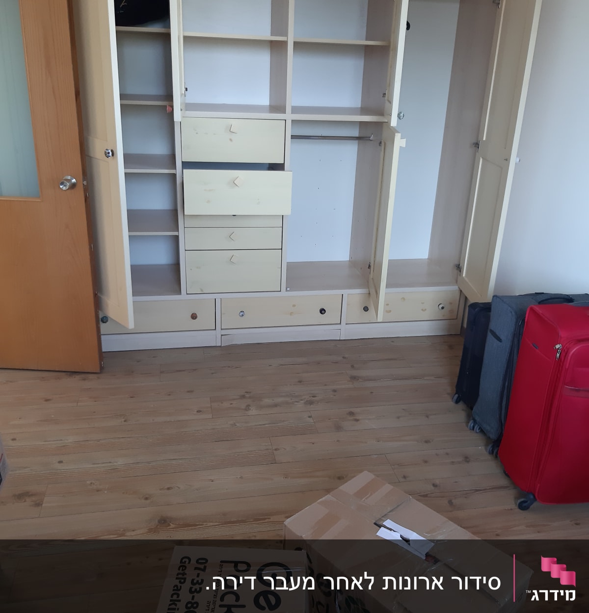 ארון פתוח עם מדפים ומגירות, קרטונים לאריזה על הרצפה